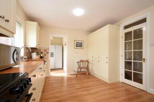 a kitchen with white cabinets and a wooden floor at Summerfold in Warkworth