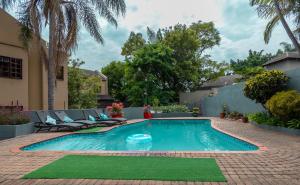 una piscina en un patio con sillas y una casa en Rozelee Rest, en Nelspruit