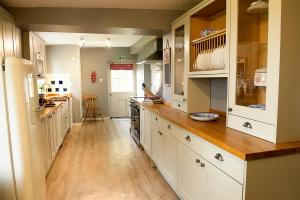 a large kitchen with white cabinets and wooden floors at Laverstock Cottage in Bridport