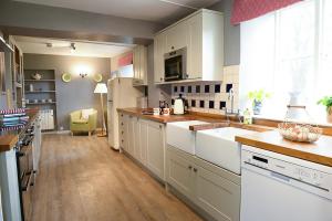 a large kitchen with white cabinets and a sink at Laverstock Cottage in Bridport