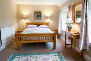 a bedroom with a bed and a desk and a window at Laverstock Cottage in Bridport +12 photos