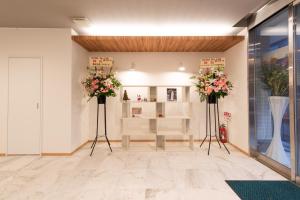 a room with two tall vases with flowers in it at Hotel The One Shinimamiya in Osaka