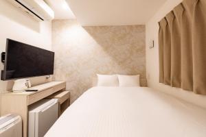 a bedroom with a large white bed and a flat screen tv at Hotel The One Shinimamiya in Osaka