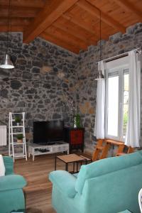 sala de estar con sofá azul y pared de piedra en LA ANTIGUA CUADRA precioso apartamento de piedra con jardín, barbacoa y acceso al río, en Ramales de la Victoria