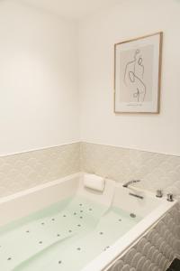 uma banheira num quarto com uma fotografia na parede em Maison 1634 - Centre historique, parking, petit-dejeuner compris, climatisation, piscine em Pézenas