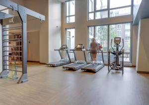 a woman in a gym with cardio equipment in a room at Wonderful 2BR Apartment At Clarendon With Gym in Arlington