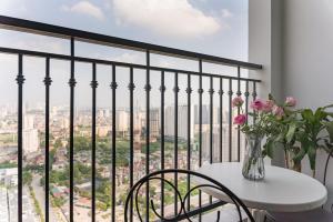 une table avec un vase de fleurs sur un balcon dans l'établissement Vinhomes Greenbay Mễ Trì Nam Từ Liêm Hà Nội, à Hanoï