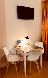 stół z dwoma białymi krzesłami i telewizor na ścianie w obiekcie Studio Loisachtal w Garmisch Partenkirchen