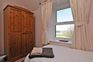 a bedroom with a bed and a large window at Turnstone Cottage in Bamburgh