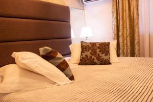 a bedroom with a bed with a headboard and pillows at Hotel Imigrantes in Bento Gonçalves