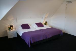 ein Schlafzimmer mit einem großen Bett mit violetter Bettwäsche in der Unterkunft De Herbergh van Flielant in Oost-Vlieland