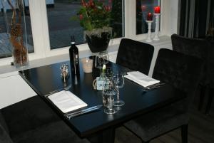 einen schwarzen Tisch mit einer Flasche Wein und Gläsern in der Unterkunft De Herbergh van Flielant in Oost-Vlieland