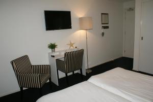 a hotel room with two beds and a television at De Herbergh van Flielant in Oost-Vlieland