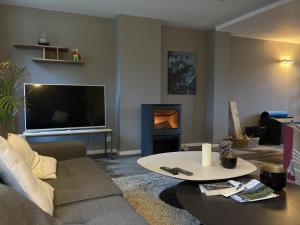 a living room with a couch and a table and a tv at Green Escape Durbuy in Durbuy