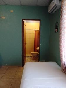 a bedroom with a bed and a bathroom with a toilet at Hostel Guayacan in Puerto Armuelles