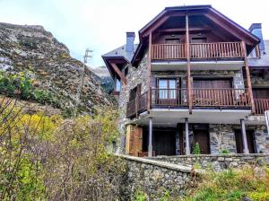 une maison avec un balcon sur le côté d'une montagne dans l'établissement Casa Churdo II - tucasaenlospirineos, à Lanuza