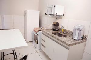 uma pequena cozinha com um lavatório e um frigorífico em 102-FLAT-Espaço, conforto. É disso que você precisa! em Anápolis
