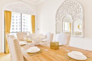 a white dining room with a table and chairs at Luxury JBR Palace! · Sea View · Free 5* Beach Resorts Access! in Dubai