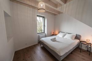 a white bedroom with a bed and a window at Maison de Village - 291 in Duingt