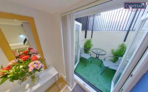 a balcony with a table and chairs and a vase of flowers at Cosy Escape - Studio Apartment in Coventry City Centre in Coventry
