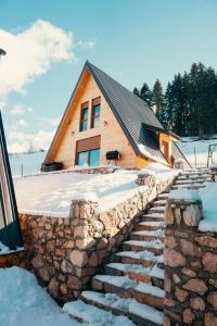 ein Haus mit einer Steinmauer und einer Treppe im Schnee in der Unterkunft Villa Route Rugove in Peja
