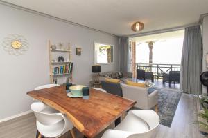 un soggiorno con tavolo in legno e sedie bianche di Brookes Hill Suites Luxury Apartment 124 a Port Elizabeth