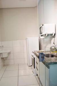 a small kitchen with a sink and a refrigerator at 104-FLAT-Espaço, conforto. É disso que você precisa! in Anápolis
