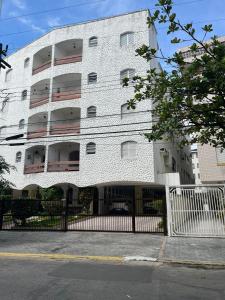 een wit gebouw met een hek ervoor bij Apartamento 2 Guarujá enseada 2 dorm, 200m praia Ed Carpentier in Guarujá