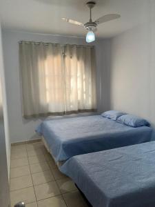 een slaapkamer met 2 bedden en een plafondventilator bij Apartamento 2 Guarujá enseada 2 dorm, 200m praia Ed Carpentier in Guarujá