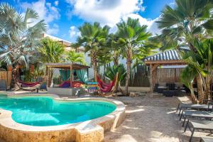 a resort pool with palm trees and hammocks at All Seasons Apartments in Kralendijk