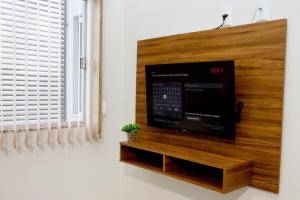 a flat screen tv sitting on top of a wooden wall at 203-FLAT-Espaço, conforto. É disso que você precisa! in Anápolis