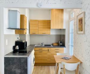 a kitchen with wooden cabinets and a wooden table at Studio équipé-climatisé avec balcon au Mourillon à 20m de la plage in Toulon