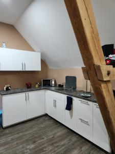 a kitchen with white cabinets and a wooden floor at Klein & Fein Aurachtal in Neundorf