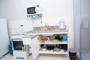 a small kitchen with a sink and a microwave at 204-FLAT-Espaço,conforto.È disso que você precisa! in Anápolis