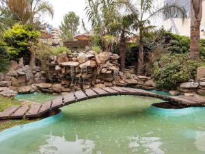 uma ponte sobre uma piscina de água num jardim em Hotel Presidente em Villa Carlos Paz