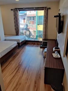 Zimmer mit 2 Betten, einem Tisch und einem Fenster in der Unterkunft Hotel Shreeji Residency in Pachmarhi