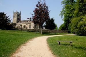 a dirt path leading to a building with a clock tower at Lydiard Park Hotel & Conference Centre in Swindon