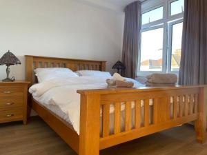 Un dormitorio con una gran cama de madera y una ventana en Premium flat! Enjoy luxurious white Egyptian bedding near Gants Hill Station, Ilford, London, en Wanstead