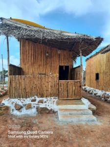 un edificio con una cabaña de madera con puerta en Moongil Kudil en Yelagiri