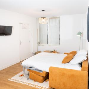 a white bedroom with a bed and two chairs at LA SUITE SEPT LE BRAS DOR in Boulogne-sur-Mer