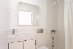 Baño blanco con lavabo y aseo en Blue Buddha Beach Rooms & Suites, en Ericeira