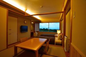 Cette chambre comprend une table, un lit et une fenêtre. dans l'établissement Senomoto Kogen Hotel, à Minamioguni