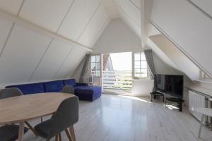 - un salon avec un canapé bleu et une table dans l'établissement Hello Zeeland - Appartement Brouwerijweg 43-2, à Domburg