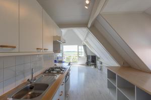 - une cuisine mansardée avec un évier et une cuisinière dans l'établissement Hello Zeeland - Appartement Brouwerijweg 43-2, à Domburg