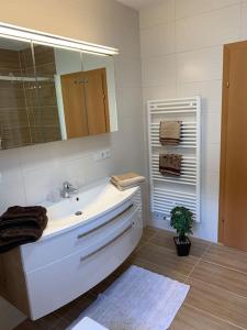 La salle de bains blanche est pourvue d'un lavabo et d'un miroir. dans l'établissement Appartement Centerbase Salzburgerland, à Sankt Veit im Pongau
