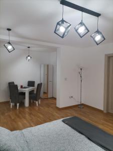 uma sala de estar com mesa, cadeiras e luzes em Apartman Mima em Sombor