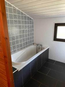 a bath tub in a bathroom with a tile wall at Yamina Lodge in Cap-Ferret