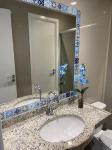 a bathroom with a sink with a mirror and blue flowers at VG FUN 308 Praia do Futuro in Fortaleza