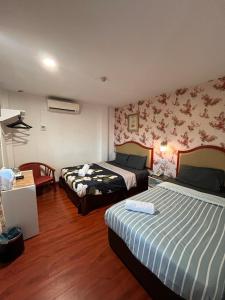 a hotel room with two beds and a desk at MR Hotel Nusa Bestari in Skudai