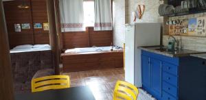 a kitchen with a refrigerator and a table and chairs at pimenta rosa guesthouse in Praia do Rosa